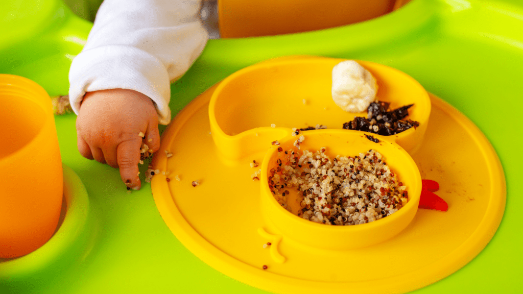 a baby in a high chair with a bowl of food