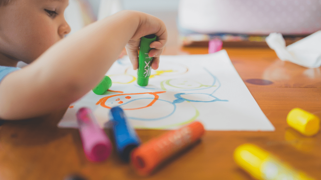 toddler drawing on paper with crayons