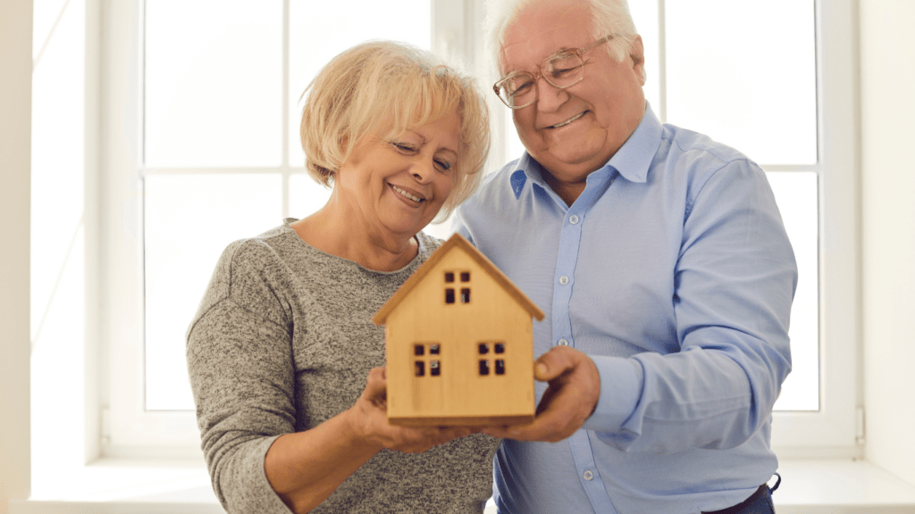 an elderly couple holding a house model