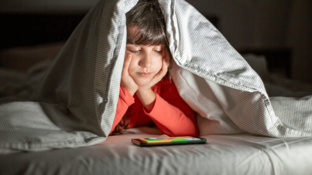 children sitting on a couch with their cell phones