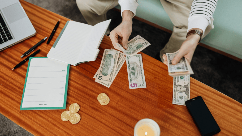 person counting money on a table in a living room