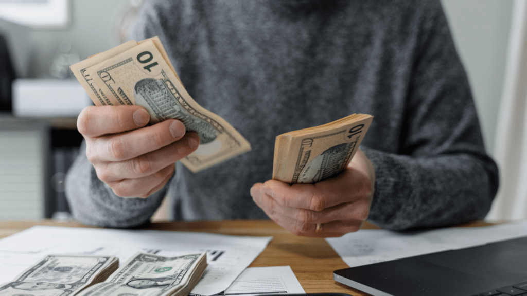 person counting money on a table in a living room