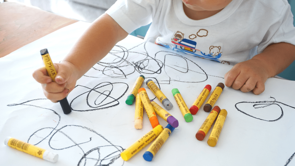 toddler drawing on paper with crayons